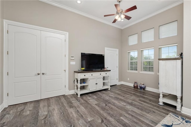 living room featuring ceiling fan, wood-type flooring, crown molding, and a high ceiling