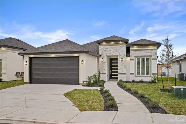 prairie-style house with a garage, central air condition unit, and a front yard