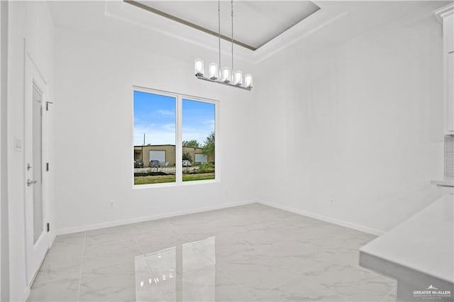 unfurnished dining area featuring a tray ceiling and a chandelier