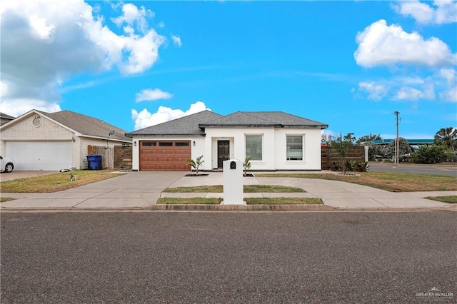 view of front of property with driveway, a garage, fence, and stucco siding