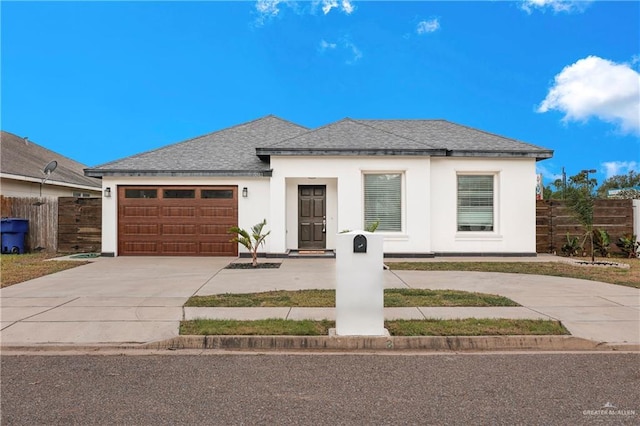 view of front of home featuring stucco siding, fence, an attached garage, a shingled roof, and concrete driveway