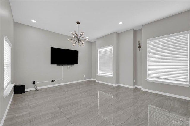 unfurnished living room with a chandelier, baseboards, and recessed lighting