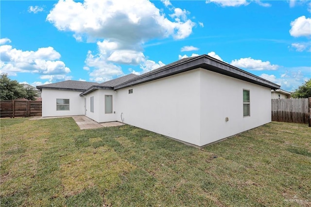 back of house featuring a yard, a fenced backyard, and stucco siding