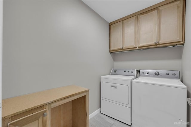 clothes washing area with cabinet space, baseboards, and separate washer and dryer