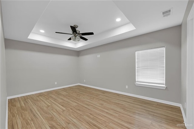spare room with visible vents, baseboards, a raised ceiling, and wood finished floors