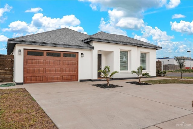 view of front of property with concrete driveway, roof with shingles, stucco siding, a garage, and fence
