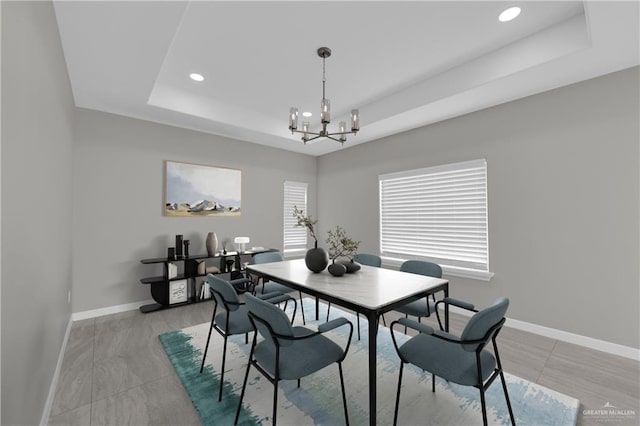 dining area with a tray ceiling, baseboards, recessed lighting, and a notable chandelier