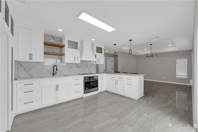 kitchen featuring stainless steel oven, a tray ceiling, a peninsula, open shelves, and custom range hood