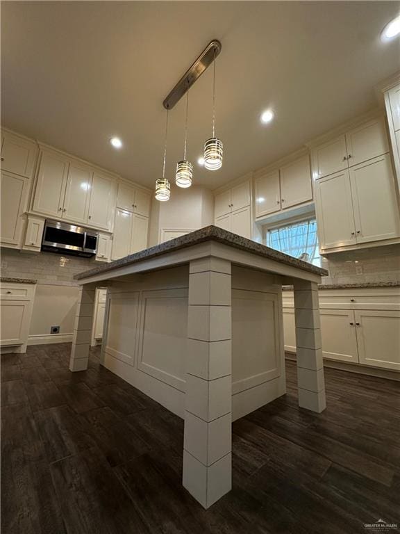 kitchen with backsplash, white cabinetry, a kitchen island, and dark wood-type flooring