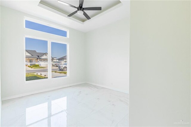 unfurnished room featuring ceiling fan and a raised ceiling