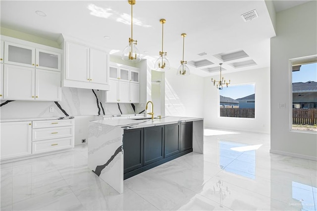 kitchen featuring pendant lighting, a center island with sink, white cabinetry, and coffered ceiling