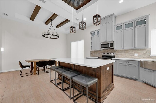 9219 N 25th St, Mcallen, TX 78504 - kitchen featuring decorative light fixtures, stainless steel appliances, light countertops, glass insert cabinets, and a kitchen island