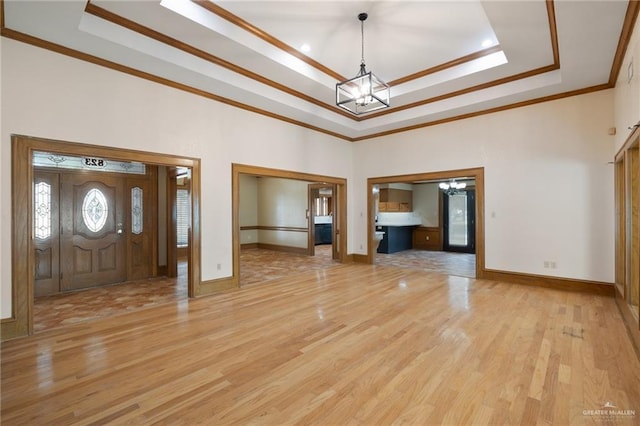 foyer featuring ornamental molding, hardwood / wood-style floors, a chandelier, and a tray ceiling