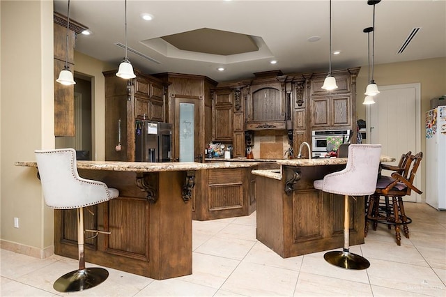 kitchen featuring a large island, a kitchen bar, stainless steel appliances, and decorative light fixtures