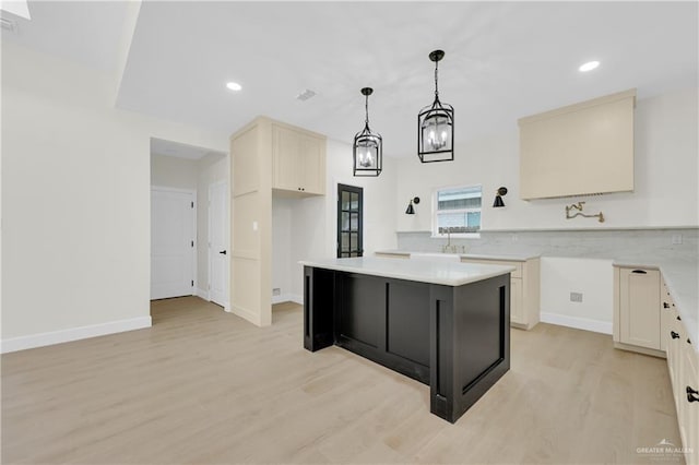 kitchen featuring sink, decorative light fixtures, light wood-type flooring, and a kitchen island