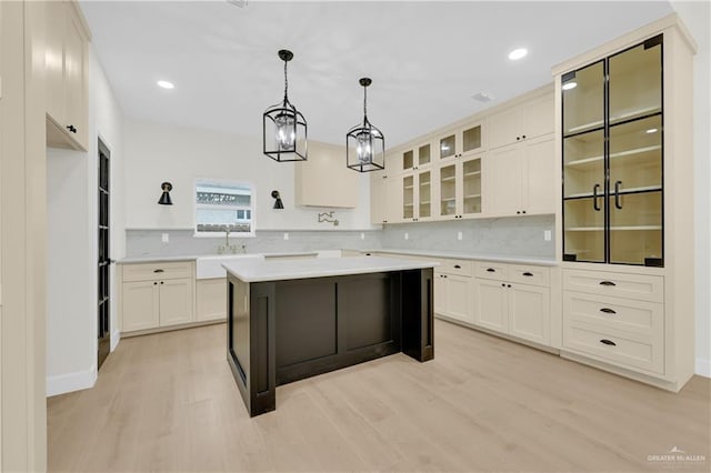 kitchen featuring white cabinetry, light wood-type flooring, a kitchen island, pendant lighting, and decorative backsplash