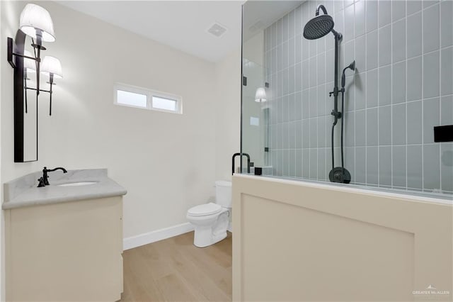 bathroom featuring vanity, wood-type flooring, a shower with door, and toilet