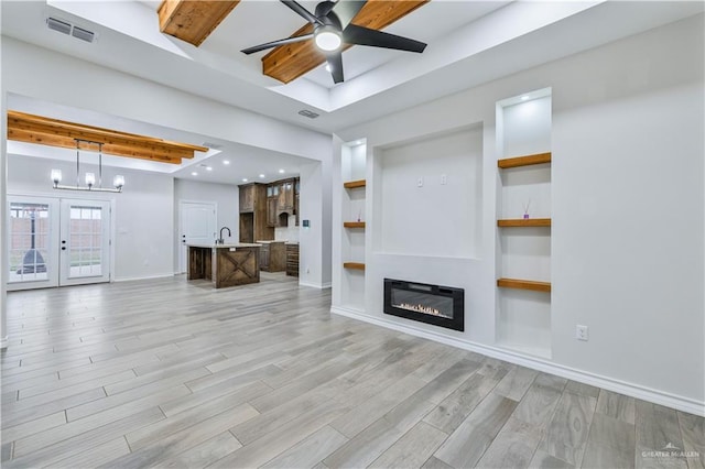 612 Spruce St, Rio Grande City, TX 78582 - unfurnished living room featuring a ceiling fan, light wood finished floors, a glass covered fireplace, a tray ceiling, and beamed ceiling