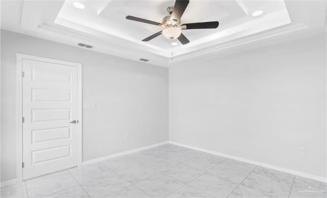 spare room featuring a raised ceiling and ceiling fan