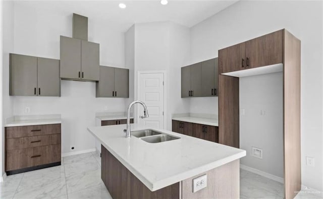 kitchen with a center island with sink, a high ceiling, and sink