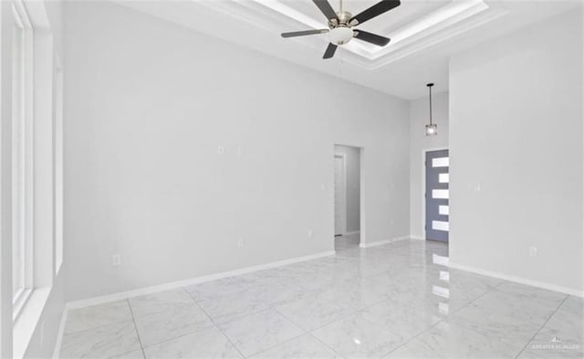 empty room with a raised ceiling and ceiling fan