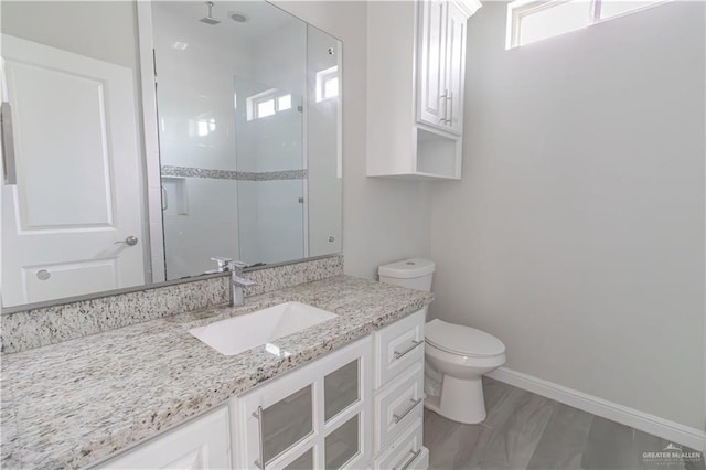 bathroom with vanity, a shower with door, and toilet