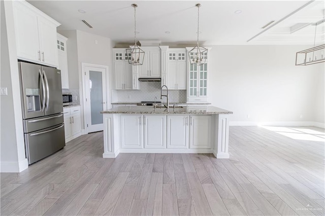 kitchen with white cabinetry, stainless steel appliances, a kitchen island with sink, and pendant lighting