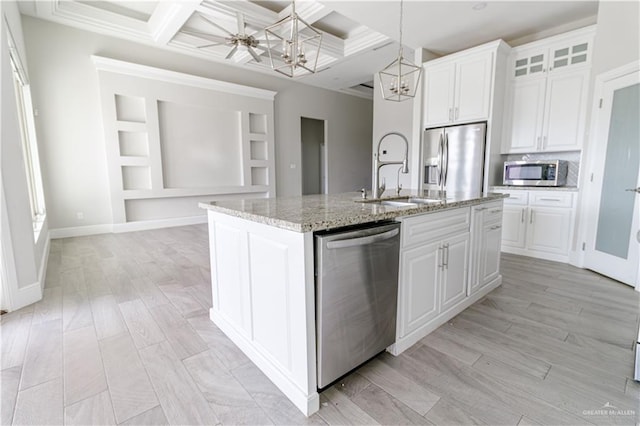 kitchen featuring stainless steel appliances, sink, an island with sink, and white cabinets