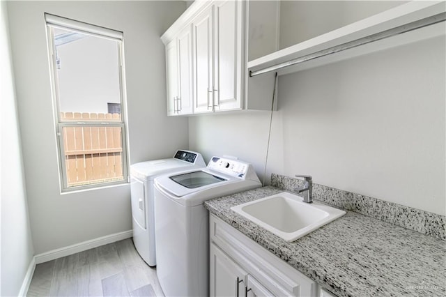 laundry area with cabinets, washer and clothes dryer, and sink