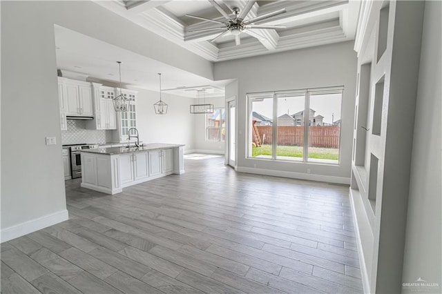 kitchen with ceiling fan, white cabinetry, hanging light fixtures, stainless steel range, and an island with sink