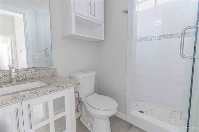 bathroom with vanity, toilet, and tiled shower