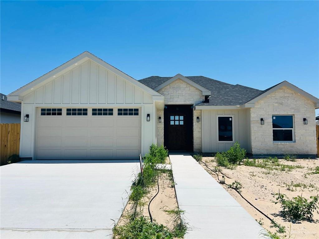 1418 Isabella Grace St, Weslaco, TX 78599 - view of front facade with board and batten siding, concrete driveway, stone siding, an attached garage, and a shingled roof