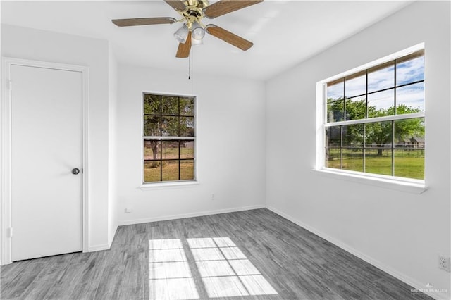 spare room with baseboards, a ceiling fan, and wood finished floors
