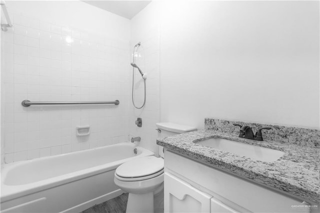 bathroom featuring wood finished floors, toilet, vanity, and shower / washtub combination