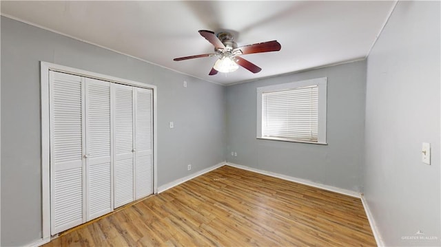 unfurnished bedroom with ceiling fan, a closet, ornamental molding, and light wood-type flooring