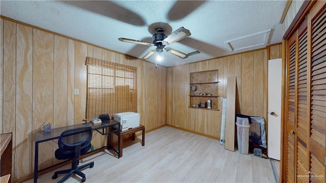 home office featuring wood walls, light hardwood / wood-style flooring, and a textured ceiling