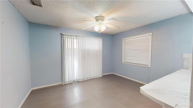 unfurnished room with ceiling fan and a textured ceiling