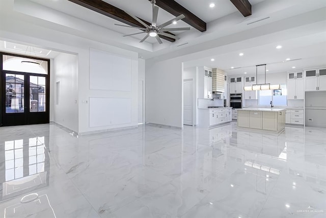 unfurnished living room featuring french doors, a sink, beam ceiling, and recessed lighting