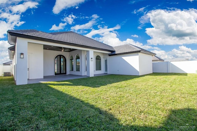 rear view of property featuring fence, a ceiling fan, a yard, french doors, and stucco siding