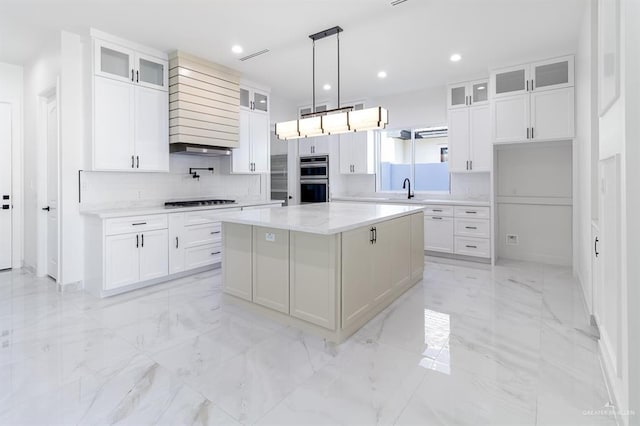 kitchen featuring marble finish floor, double oven, a kitchen island, and white cabinetry