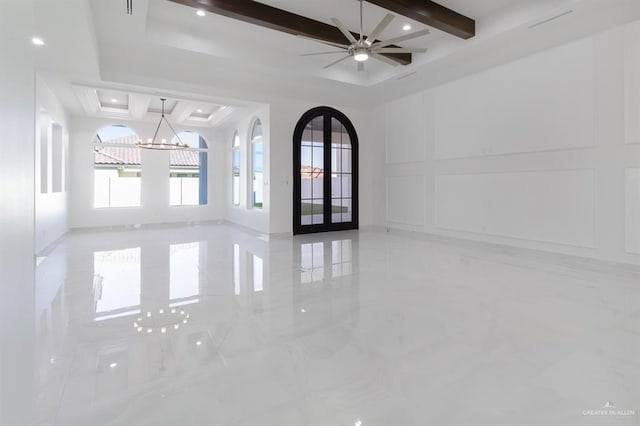 unfurnished room featuring arched walkways, marble finish floor, french doors, a decorative wall, and beam ceiling