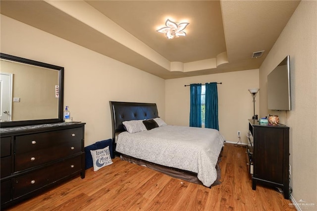 bedroom featuring light hardwood / wood-style floors and a tray ceiling