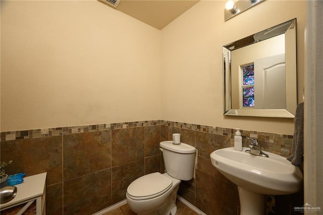 bathroom with sink, toilet, and tile walls