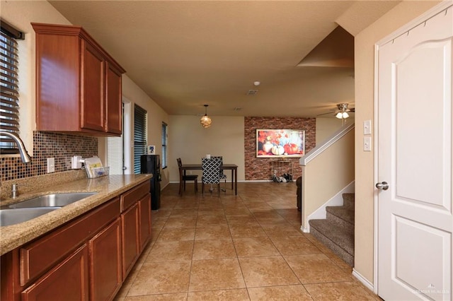 kitchen featuring ceiling fan, sink, hanging light fixtures, backsplash, and light tile patterned floors