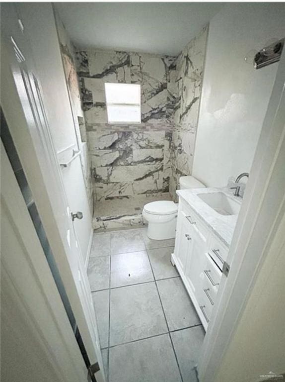 bathroom with a shower, tile patterned flooring, vanity, and toilet