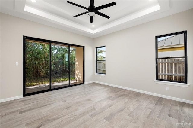 unfurnished room featuring ceiling fan, light hardwood / wood-style floors, and a raised ceiling