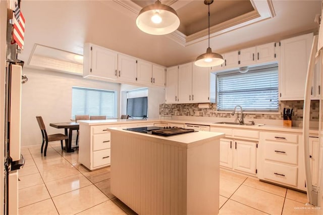 kitchen with a raised ceiling, white cabinetry, a kitchen island, and sink