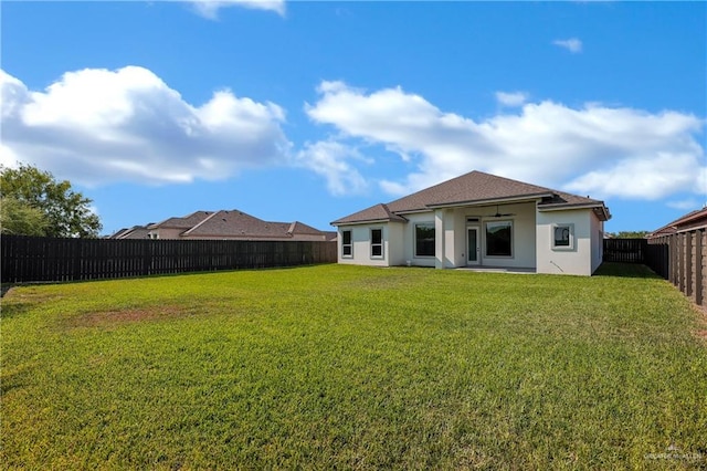 rear view of property with a yard and ceiling fan