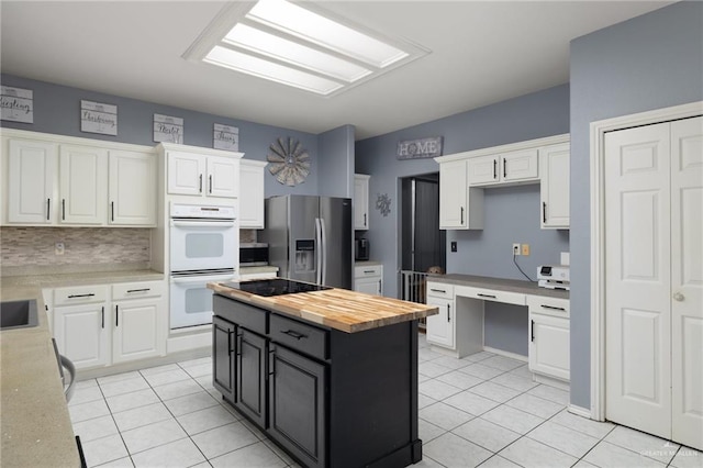 kitchen featuring wood counters, backsplash, white cabinets, light tile patterned flooring, and stainless steel appliances