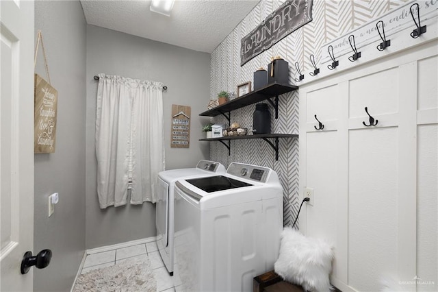 clothes washing area featuring washer and dryer, light tile patterned floors, and a textured ceiling